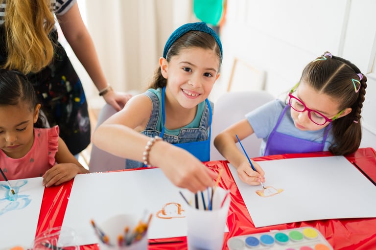 Elementary school students enjoying painting watercolors with their art teacher during creative class