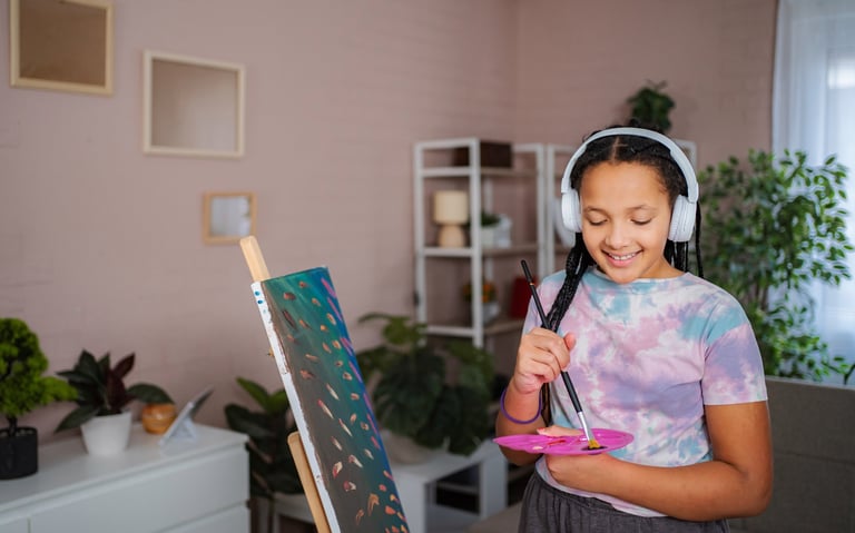Young girl painting a colorful art piece while listening to music in a bright creative space